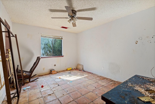 empty room with a textured ceiling, ceiling fan, and visible vents