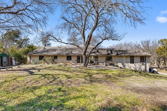 back of property with an outbuilding, a patio area, a yard, and a storage unit