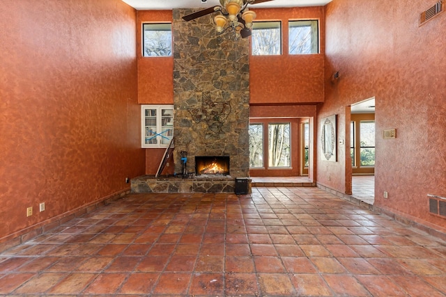 unfurnished living room featuring a ceiling fan, tile patterned flooring, visible vents, and a fireplace