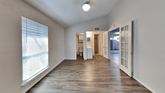 empty room featuring baseboards, visible vents, lofted ceiling, dark wood-style flooring, and french doors