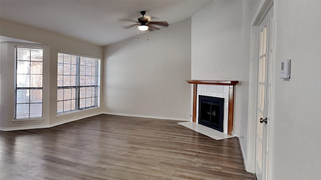 unfurnished living room with ceiling fan, baseboards, wood finished floors, and a tile fireplace