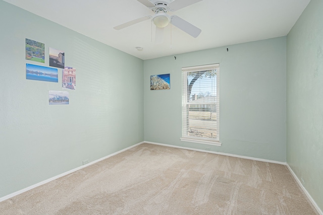 carpeted spare room featuring baseboards and a ceiling fan