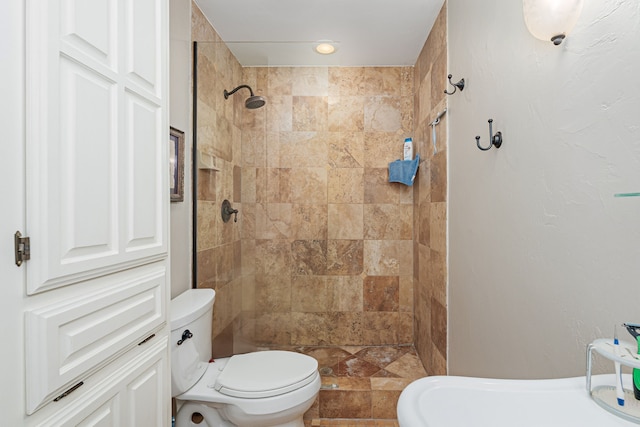 bathroom with a tile shower and toilet