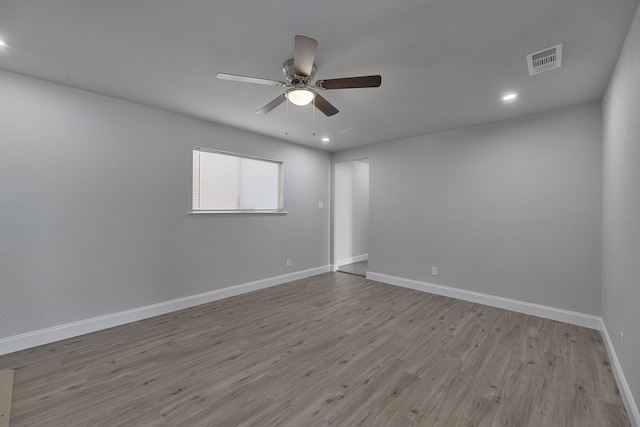 spare room with recessed lighting, wood finished floors, a ceiling fan, visible vents, and baseboards