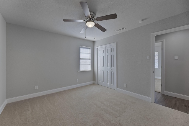 unfurnished bedroom with carpet, a closet, visible vents, and a textured ceiling