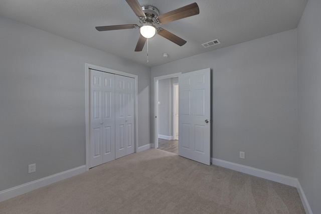 unfurnished bedroom with ceiling fan, light colored carpet, visible vents, baseboards, and a closet