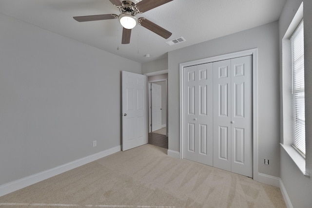 unfurnished bedroom with ceiling fan, carpet flooring, visible vents, baseboards, and a closet