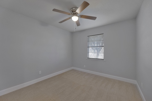 empty room with light carpet, a textured ceiling, a ceiling fan, and baseboards