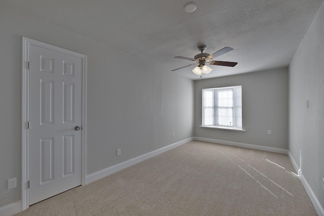 carpeted empty room with a textured ceiling, ceiling fan, and baseboards