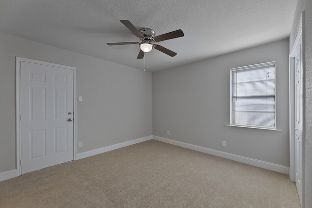 spare room featuring light carpet, a textured ceiling, and baseboards