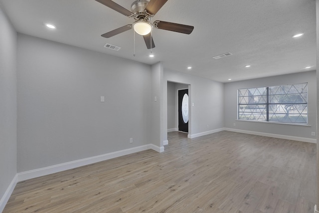 spare room with light wood-type flooring, visible vents, and baseboards