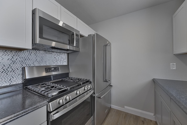 kitchen with stainless steel appliances, dark countertops, and white cabinetry