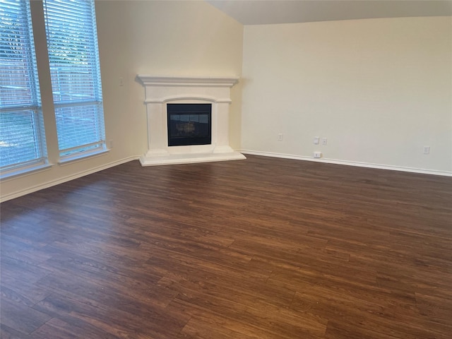 unfurnished living room with dark wood-type flooring, a glass covered fireplace, and baseboards