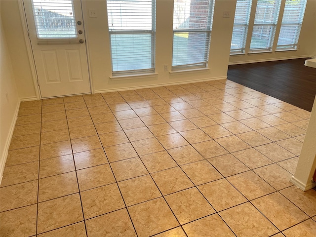 doorway featuring baseboards and light tile patterned floors