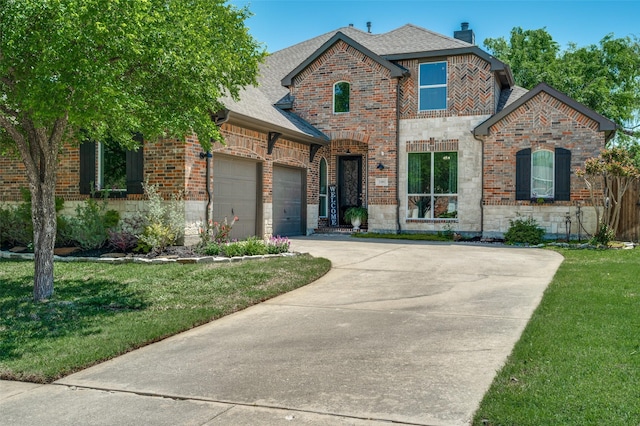 view of front of home with a garage, driveway, a front yard, and brick siding