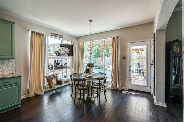 dining space with dark wood-style floors, baseboards, and an inviting chandelier