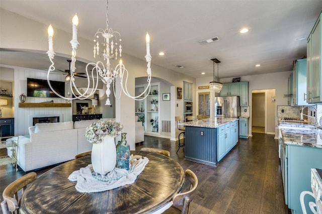 dining area featuring an inviting chandelier, a fireplace, visible vents, and dark wood finished floors