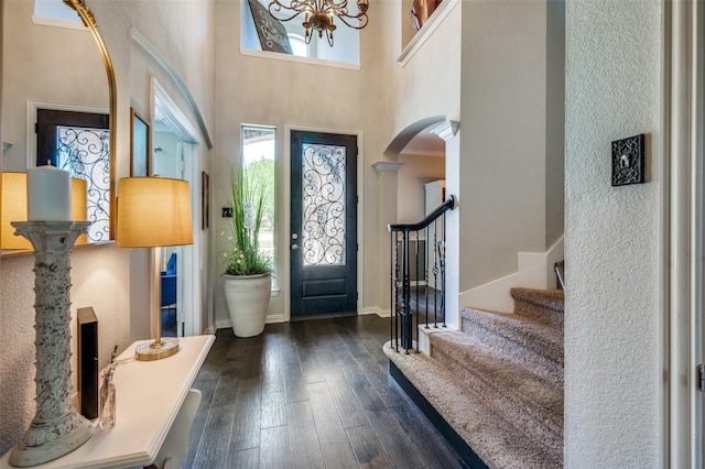 entryway featuring arched walkways, a high ceiling, dark wood-type flooring, baseboards, and stairs