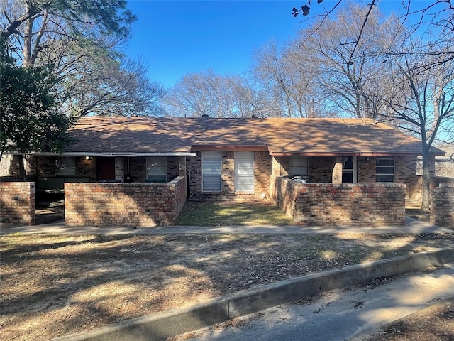 ranch-style house featuring a shingled roof and brick siding