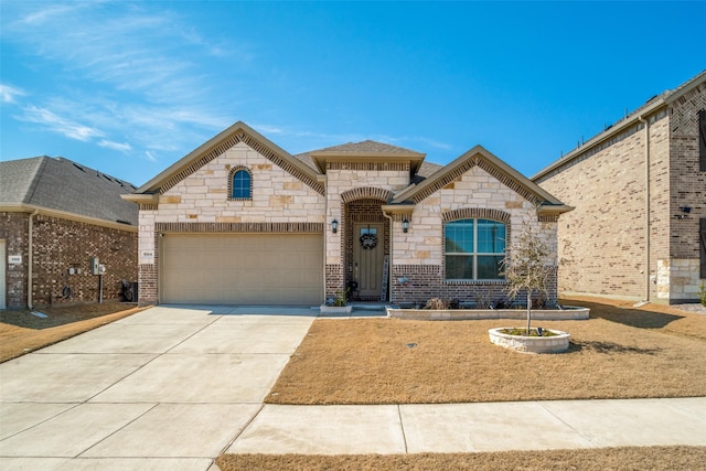 french country inspired facade featuring driveway, an attached garage, and brick siding