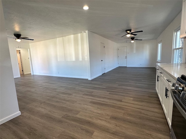 interior space featuring a ceiling fan, dark wood-style flooring, a textured ceiling, and baseboards