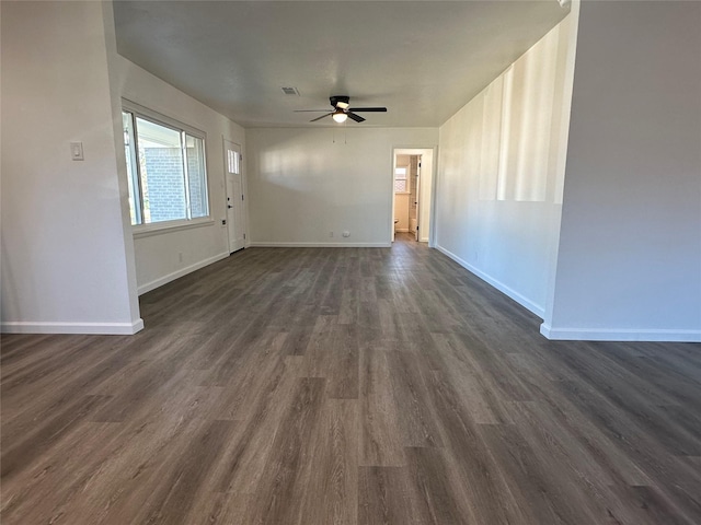 unfurnished living room with dark wood-style floors, visible vents, baseboards, and a ceiling fan