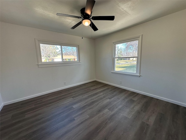 empty room with ceiling fan, a textured ceiling, baseboards, and dark wood-style flooring