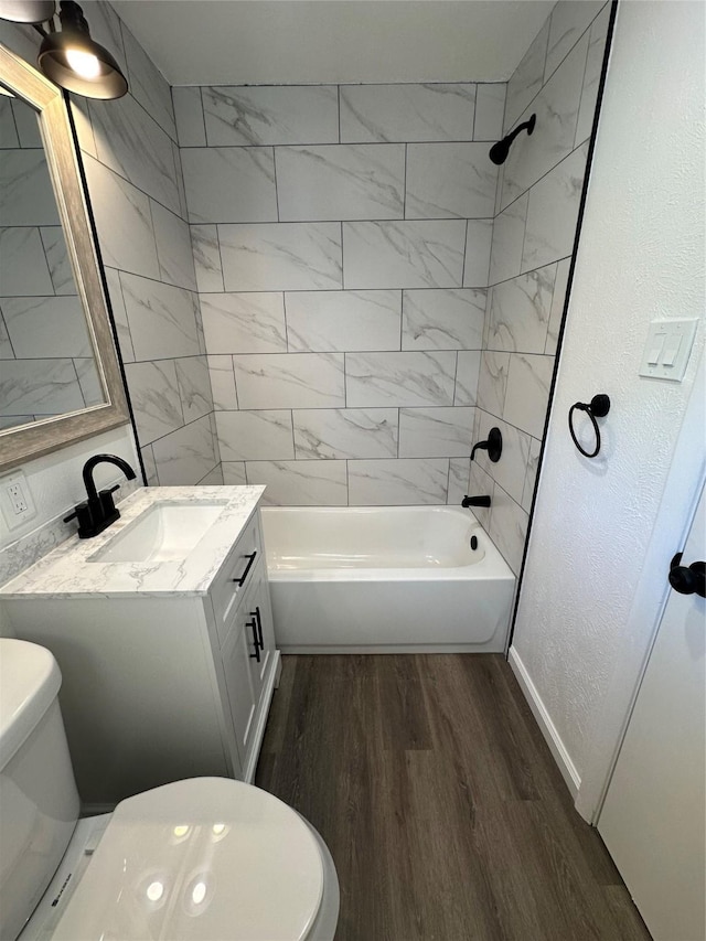 full bath with a textured wall, toilet, wood finished floors,  shower combination, and vanity