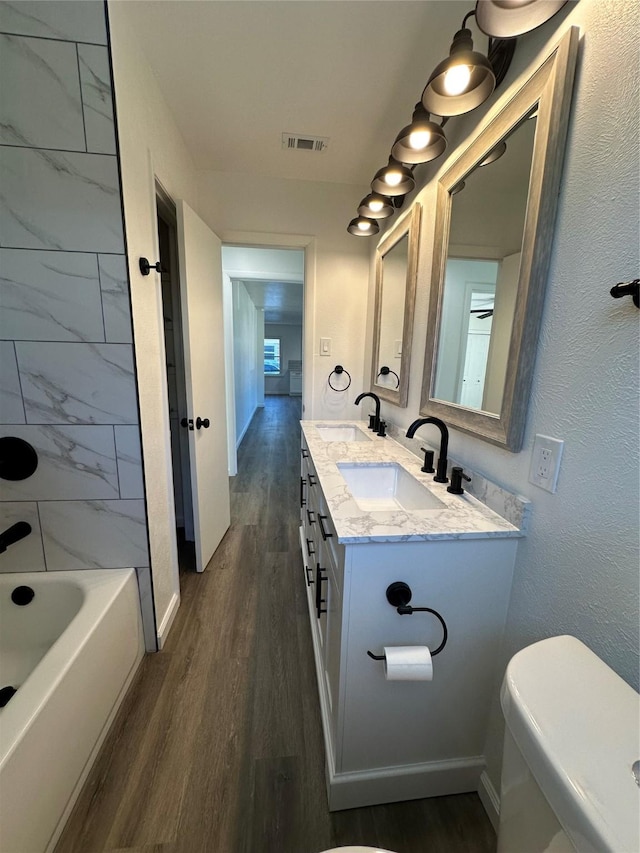 bathroom featuring visible vents, a sink, and wood finished floors