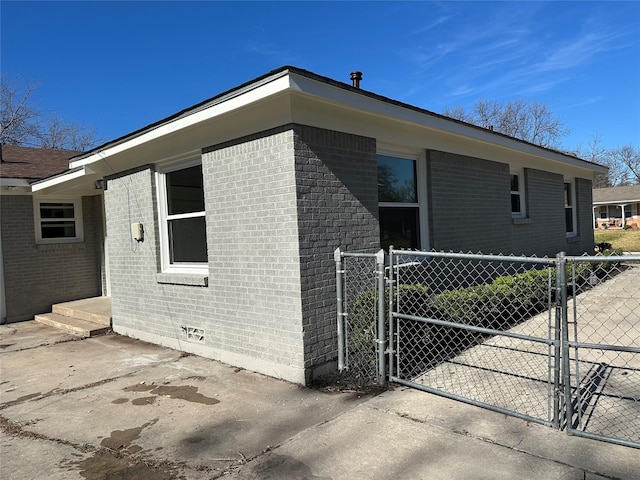 view of side of home featuring a gate, brick siding, fence, and crawl space