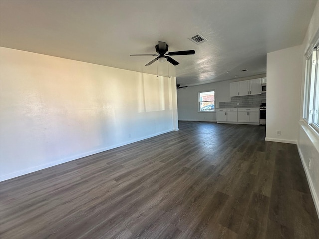 unfurnished living room featuring dark wood-style floors, visible vents, baseboards, and a ceiling fan