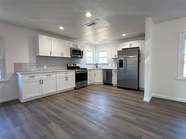 kitchen with tasteful backsplash, visible vents, appliances with stainless steel finishes, and white cabinets