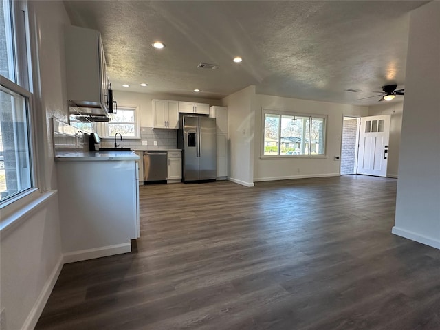 kitchen with dark wood finished floors, tasteful backsplash, appliances with stainless steel finishes, a sink, and baseboards