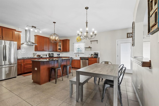 kitchen with a breakfast bar area, a center island, stainless steel appliances, wall chimney range hood, and backsplash