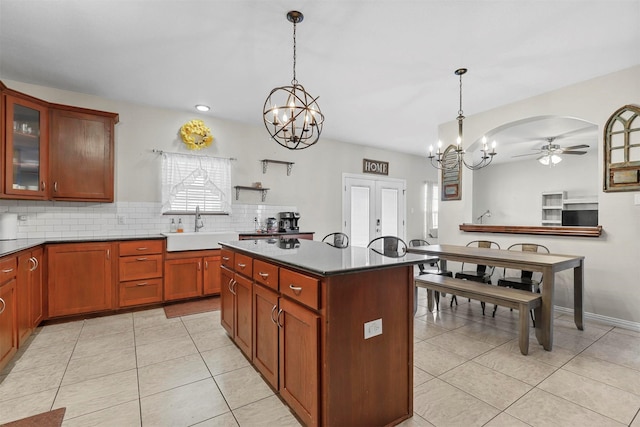 kitchen featuring light tile patterned floors, decorative backsplash, french doors, a sink, and ceiling fan with notable chandelier