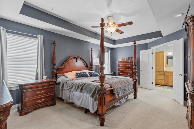 bedroom featuring baseboards, a tray ceiling, a ceiling fan, and light colored carpet