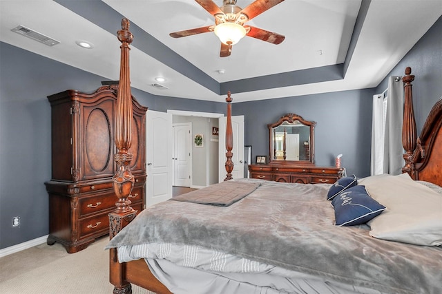 bedroom with baseboards, a raised ceiling, visible vents, and light colored carpet