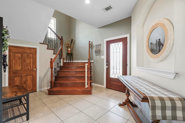 foyer featuring light tile patterned floors, stairs, visible vents, and baseboards