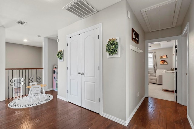 hallway featuring attic access, visible vents, and hardwood / wood-style floors