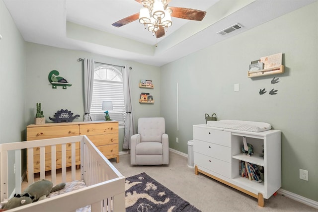 bedroom with light carpet, visible vents, baseboards, a crib, and a raised ceiling