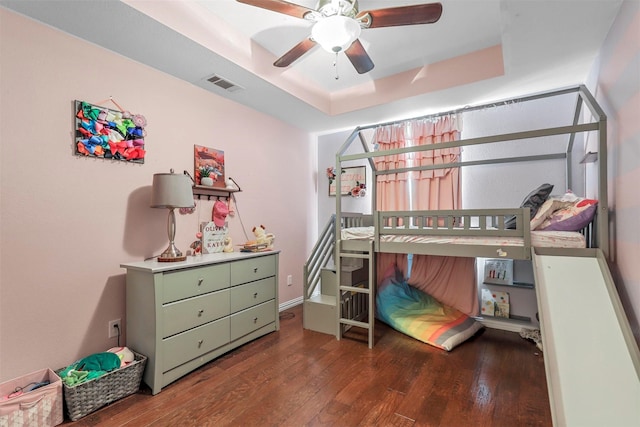 bedroom with ceiling fan, wood finished floors, a raised ceiling, and visible vents