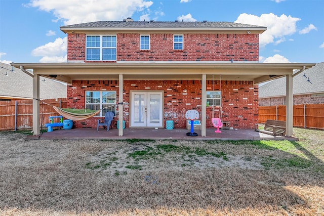 rear view of house featuring fence, a patio, and brick siding