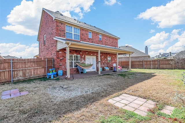 rear view of property featuring a yard, a fenced backyard, a patio, and brick siding