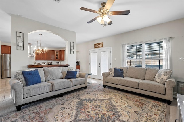 living area featuring arched walkways, visible vents, and ceiling fan with notable chandelier