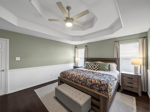 bedroom featuring a wainscoted wall, ceiling fan, hardwood / wood-style floors, and a raised ceiling