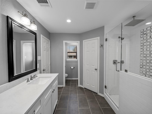 full bathroom with toilet, vanity, a shower stall, and visible vents