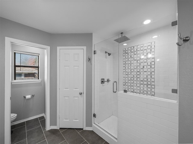 full bath featuring tile patterned flooring, baseboards, a shower stall, and toilet