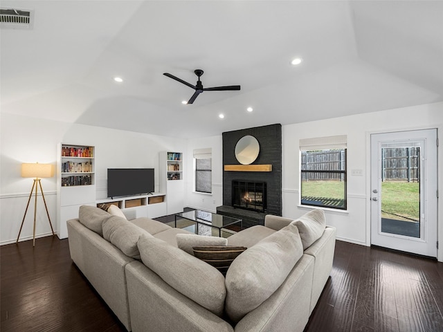 living area featuring recessed lighting, a large fireplace, visible vents, vaulted ceiling, and dark wood-style floors