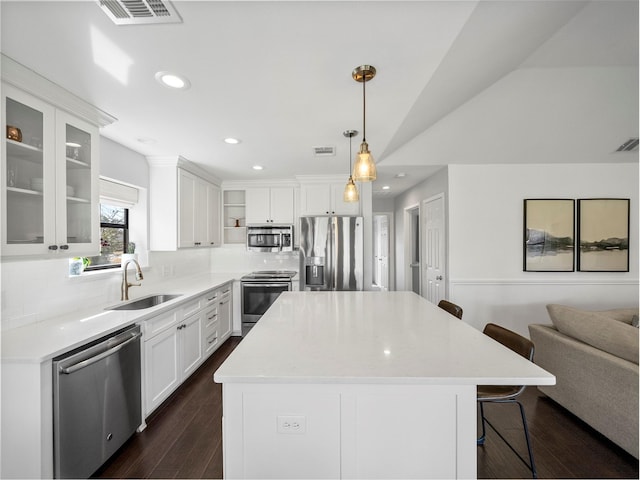 kitchen featuring visible vents, appliances with stainless steel finishes, a kitchen breakfast bar, open shelves, and a sink