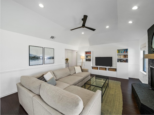 living area featuring visible vents, lofted ceiling, ceiling fan, dark wood-type flooring, and a fireplace